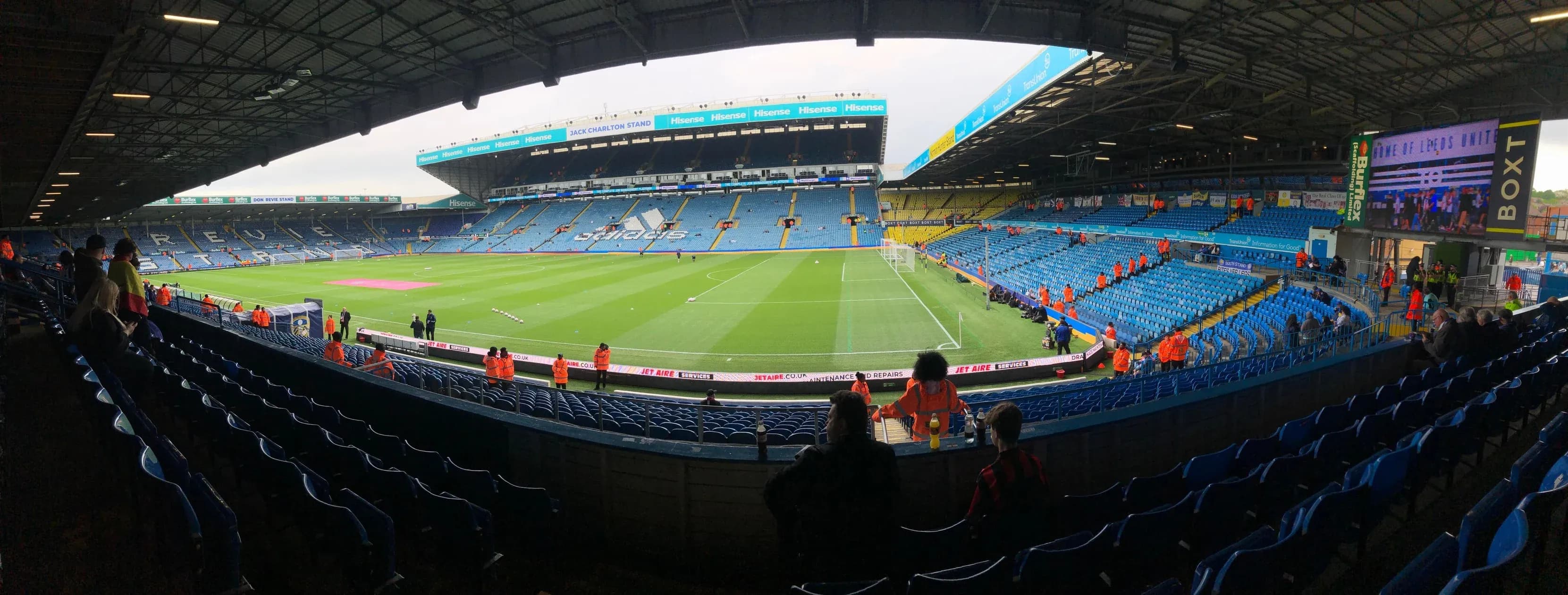Panoramic view of Elland Road stadium interior with empty blue seats and green pitch before kick-off