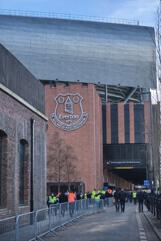 The outside of Hill Dickinson Stadium with the Everton crest as fans walk toward the entrances.