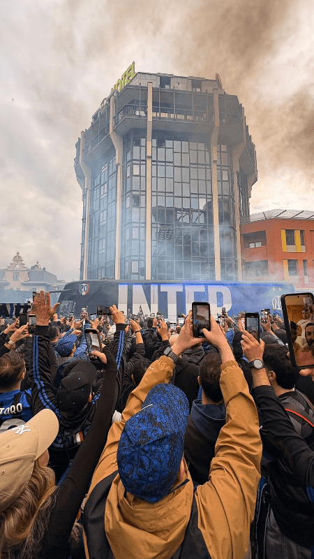 Inter Milan fans welcoming the team bus with blue smoke flares and phones raised outside the stadium in Milan