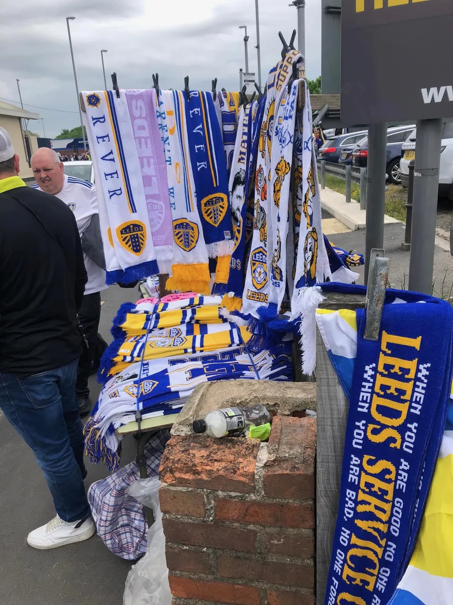 Street vendor selling Leeds United scarves in blue, white and yellow outside Elland Road on matchday